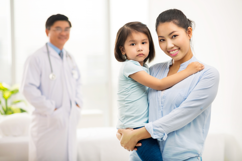 Portrait of Asian mother and her daughter, pediatrician standing in the background
